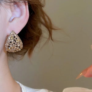 Close-up of sparkling hollow teardrop earrings with crystals worn by a model