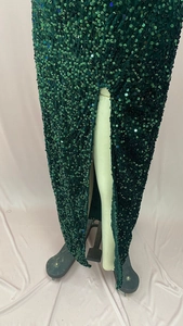 Détail d'une robe de soirée à paillettes vert foncé avec texture et fente latérale