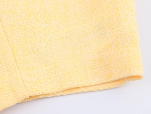 Vista macro ravvicinata della trama del tessuto in tweed giallo e delle cuciture della giacca