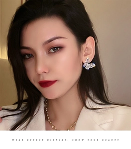 Close-up of sparkling silver butterfly stud earrings with rhinestones on a female model