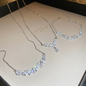 Close-up of V-shaped silver necklace and bracelet set with cubic zirconia on display tray