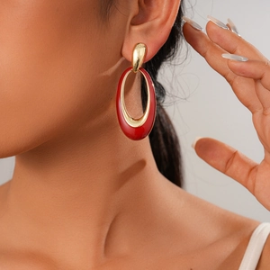 Close-up of a model wearing elegant red resin oval earrings with gold metal accents