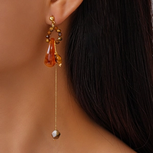 Close-up of amber beads and resin pendant earrings on a model with long hair