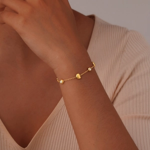 Bracelet coeur doré avec pierres en zircon porté au poignet pour un look élégant et pur