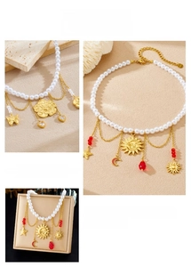 Close-up of pearl chain with gold celestial pendants and red bead accents