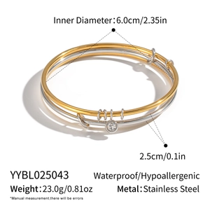 Macro shot of layered gold and silver steel bracelet with a cubic zirconia pendant