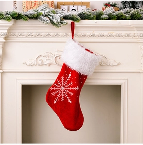 Détail de chaussette de Noël en velours rouge avec flocons argentés sur cheminée