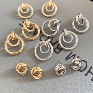 Détail des boucles d'oreilles circulaires creuses dorées et argentées au fini texturé