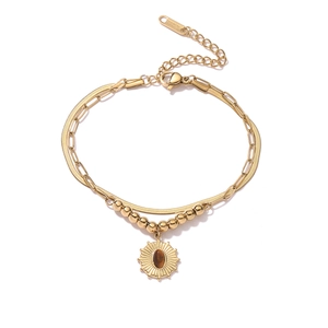 Detail of gold double-layer stainless steel bracelet with sunflower and brown gem pendant