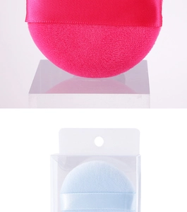 Detail view of pink and light blue plush powder puffs with ribbon handles in clear packaging
