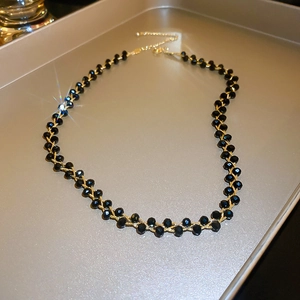 Detail of elegant gold-plated choker with black faceted beads and lobster clasp