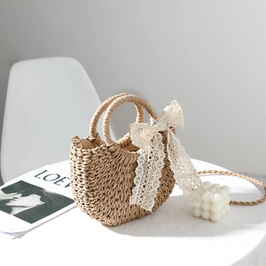 Handcrafted straw handbag with cream lace bow and long woven strap for beach vacations