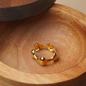 Detailed view of a gold irregular wavy textured ring placed on a warm wooden surface