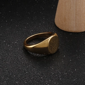 Detailed view of polished 18K gold plated stainless steel signet ring on black texture
