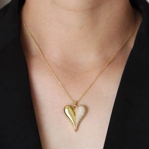 Elegant gold heart pendant necklace with white cubic zirconia worn on a black blazer