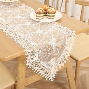 Detailed view of white French lace table runner, floral embroidery, elegant dining decor.