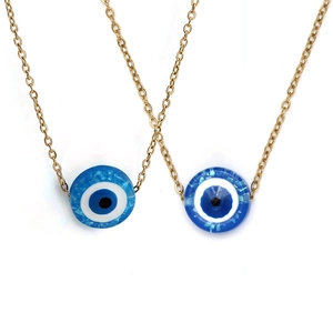 Detail view of two gold metal necklaces featuring blue round evil eye resin pendants