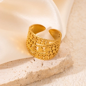 Detail of a golden multi-layer cutout ring on a travertine stone with silk backdrop