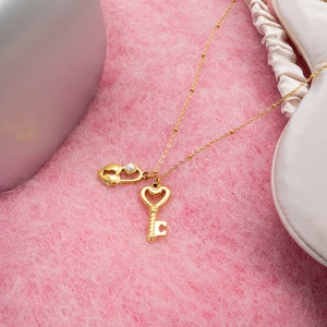 Détail du pendentif cœur avec serrure et clé dorées sur une surface en velours