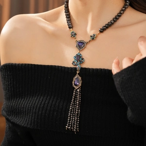 Détail du collier chaîne serpent vintage avec pierres violettes et pendentif à pompon noir