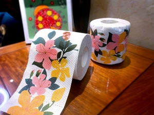 Detail of toilet paper rolls featuring colorful floral prints in pink and green patterns