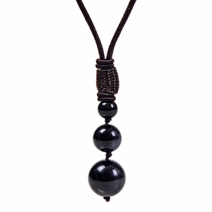 Vue détaillée de trois perles d'obsidienne noire polie sur un cordon tressé marron