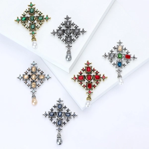 Detailed close-up of colorful gemstone baroque cross brooches with pearl pendants