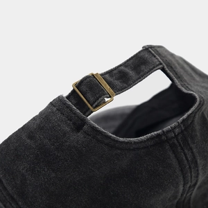 Close-up of adjustable metal buckle on vintage washed grey baseball cap with twill texture