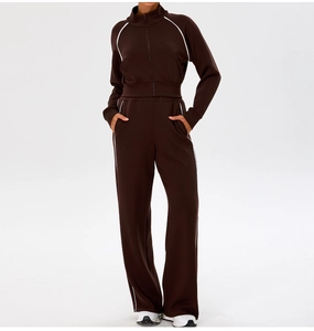 Detail of a dark brown yoga set with white contrast piping on the jacket and trousers