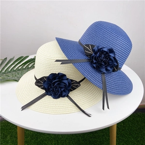 Detail of straw sun hats with 3D navy blue flower decorations on round wide brims