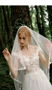 Detail of white lawn wedding dress featuring intricate lace embroidery and beaded bodice