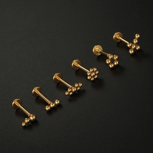 Détail de six piercings en acier inoxydable doré avec divers motifs de perles