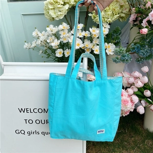 Detalle del bolso tote de lona azul claro con asas dobles y diseño de forro a cuadros