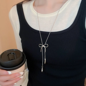 Detail of silver bowknot pendant necklace with long tassel chain on a casual outfit