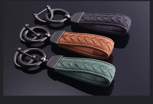 Detailed view of woven suede car keychains in black, brown, and green with matte hardware