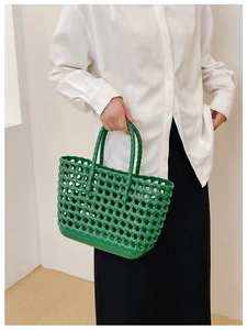 Detailed view of green woven hollow jelly bag held by model for summer beach vacation