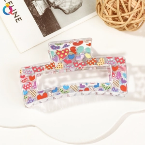Detailed macro view of acrylic hair claw clip with colorful heart pattern prints