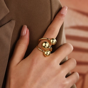 Detail of three-tier golden sphere ring on hand with elegant polished finish