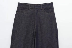 Detail of high-waisted denim pants featuring a metal zipper fly and symmetric front pockets