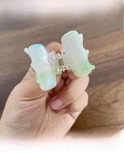 Detailed view of mini butterfly hair claw clip in iridescent pearlescent green color