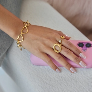 Detail of 18K gold-plated heart chain bracelet and pearl ring on model hand