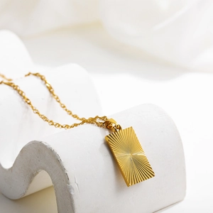 Detailed close-up of 18k gold butterfly heart pendant with radial brushed texture