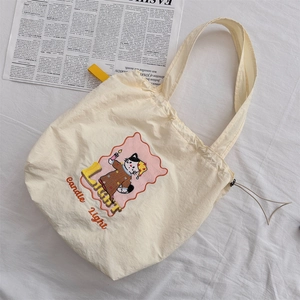 Close-up of cream canvas tote bag featuring cute cartoon cat and candle light text