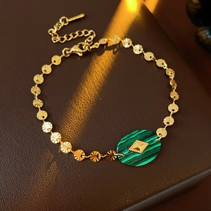 Détail du bracelet vintage doré avec pierre malachite verte sur fond en cuir marron