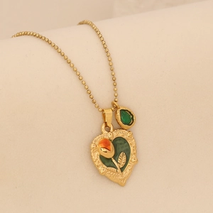 Détail macro d'un pendentif cœur vintage avec tulipe rouge et pierre verte
