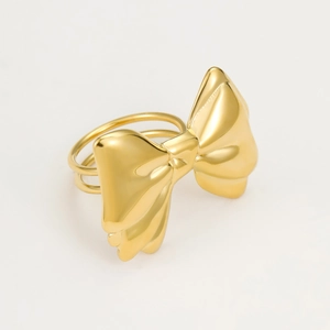 Polished gold metal bow ring with dual-band structure on a minimalist background