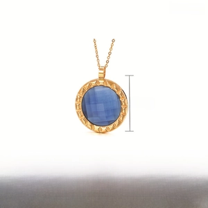 Macro shot of 40mm round blue crystal pendant with gold-plated stainless steel textured frame