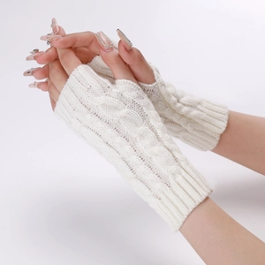 Close-up of white cable knit fingerless gloves showing soft texture and twisted patterns