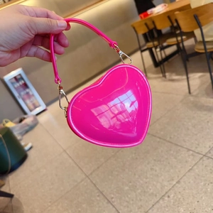 Detail of a bright pink heart-shaped mini jelly bag with metallic gold hooks and glossy finish