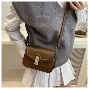 Detail einer dunkelbraunen Leder-Umhängetasche mit Vintage-Stil und Goldschloss